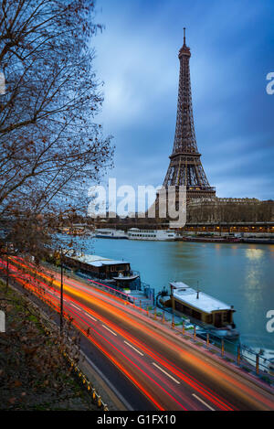 Eiffel Tower at twilight on a cloudy winter morning with the Seine River and car light trails. Paris, 7th Arrondissement, France Stock Photo