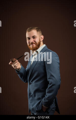 Elegant smiling man with beard holding smoking pipe Stock Photo