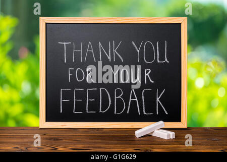handwriting text thank you for your feedback is written in chalkboard on green light background and rustic wooden board, close u Stock Photo