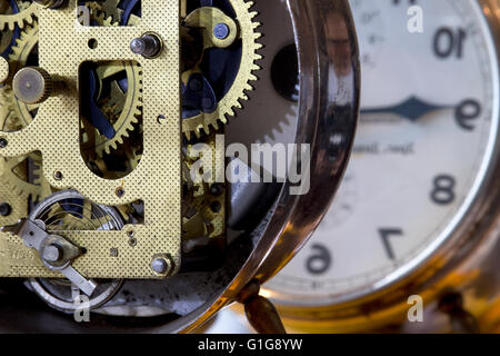 An old mechanical alarm clock with visible mechanism set in front of the mirror Stock Photo