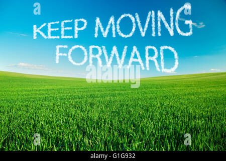 Keep moving forward written in clouds over green field Stock Photo