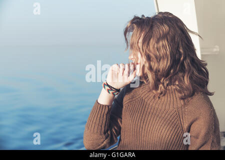 Beautiful relaxing blond teenage girl stands on the walking deck of cruise ship, close-up outdoor portrait Stock Photo