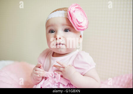 portrait of cute little baby girl with pink bow flower on her head Stock Photo