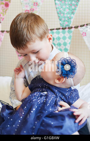 Happy little boy playing with a baby, his sister indoors Stock Photo