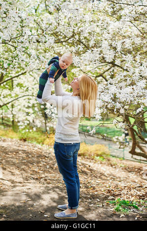 Little baby boy with young mother in the spring blossom garden Stock Photo