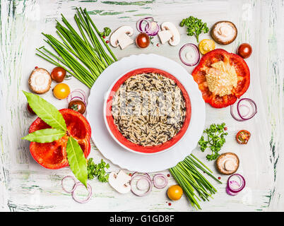 Wild rice dish and various vegetables and seasoning ingredients for tasty vegetarian cooking on light  rustic wooden background, Stock Photo