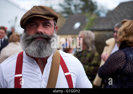 Portrait of a mature man in traditional clothes with flat cap, grandad shirt and red braces with a large, bushy greying beard. A hipster. Stock Photo