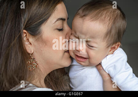 Young mother trying to comfort and calm down her crying baby boy. Stock Photo