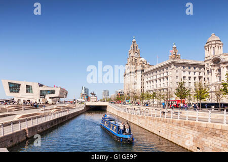 A narrowboat passing through the Liverpool Canal Link, in front of the Three Graces and the Mersey Ferries Building, Liverpool, Stock Photo