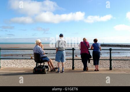 Elderly people looking out to sea on Sidmouth seafront in summer Stock Photo