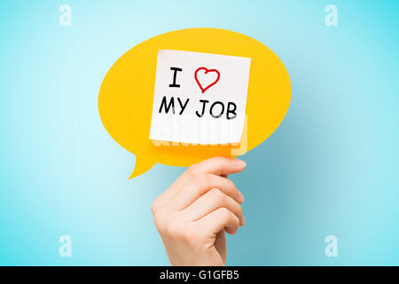 Adhesive note on yellow speech bubble with "I love my job" words on blue background. Stock Photo