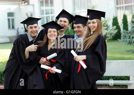 Group of laughing university graduates with diplomas in their hands Stock Photo