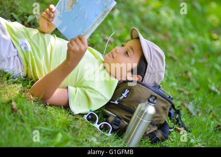 Young boy lying in the grass looking at a map Stock Photo