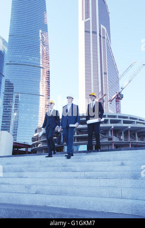 Architects with blueprint at skyscrapers background Stock Photo