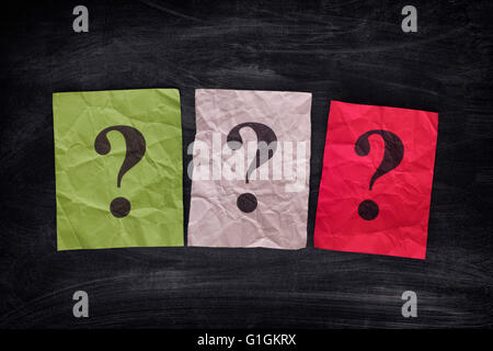 Colorful paper notes with question marks on black board. Close up. Stock Photo