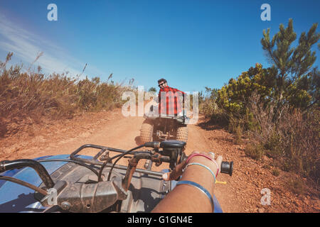 Young man driving a quad bike on country road. Young man on an all terrain vehicle in nature. POV shot. Stock Photo
