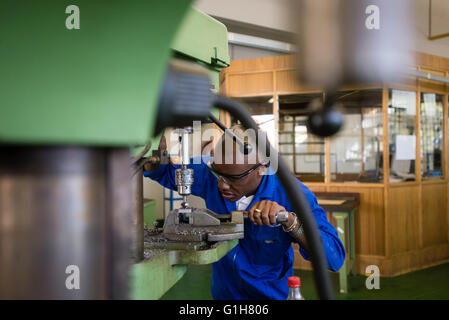 Fitting and Turning Trade of the Windhoek Vocational Training Centre, Namibia. Student works with a drill machine making holes through a piece of steel Stock Photo
