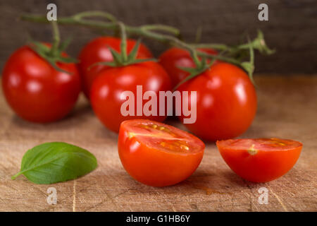 Cut in half cherry tomato with basil leaf on wood table Stock Photo