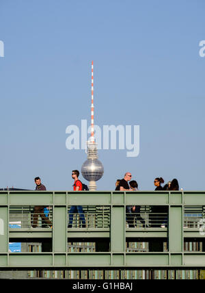 Pedestrians walk over footbridge crossing River Spree with Fernsehturm , television tower, to rear in Berlin Germany Stock Photo