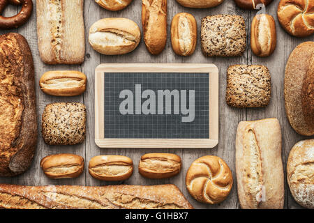 Fresh crisp bread on a wooden worktop and blank chalkboard, bakery and healthy eating concept, flat lay banner Stock Photo