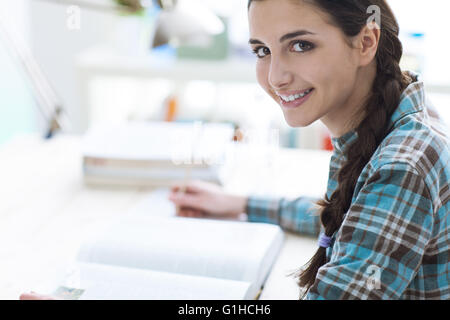 Smiling young student girl studying and reading a book, education and learning concept Stock Photo
