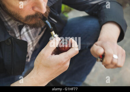 Bearded man smoking pipe, outdoor photo with selective focus Stock Photo
