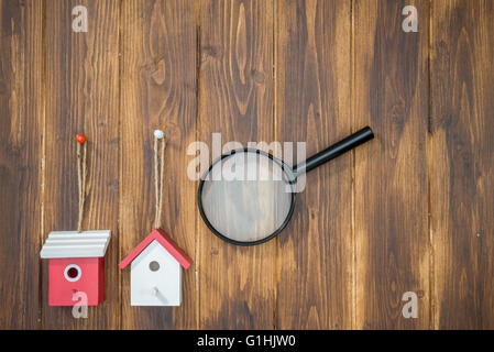 model house with Magnifying Glass on wooden background, House hunting Stock Photo
