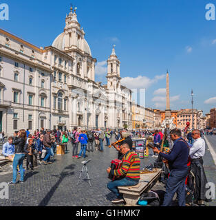 Rome, Italy.  Piazza Navona.   A group of street musicians ply their trade in front of the church of Sant'Agnese in Agone. Stock Photo
