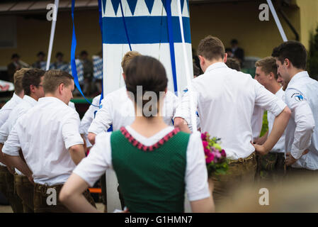 Woman in local dress and young men in leather trouser dancing a traditional bavarian folk dance around a maypole,Bavaria,Germany Stock Photo