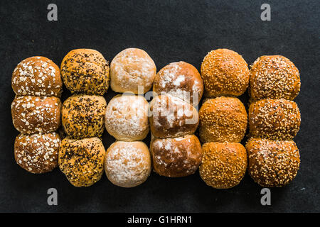 Artisan bakery buns and rolls on dark slate background from above Stock Photo