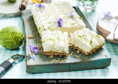 taste of summer, key lime pie with flowers, sliced and served on wooden board Stock Photo