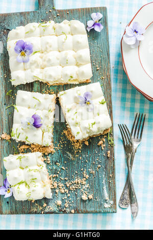 taste of summer, key lime pie with flowers, sliced and served on wooden board Stock Photo