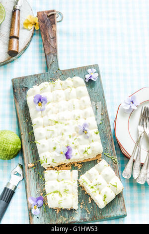 taste of summer, key lime pie with flowers, sliced and served on wooden board Stock Photo