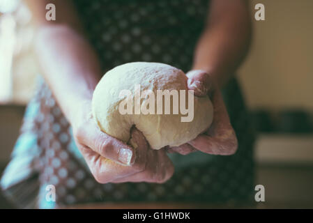 A woman kneads bread dough in her home kitchen. Stock Photo