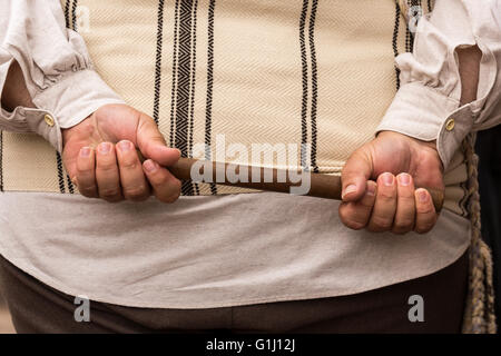 Man holding wooden baton in both hands behind his back Stock Photo