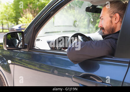 Serious Asian man as a driver of modern Japanese suv looks in open car window, outdoor portrait Stock Photo
