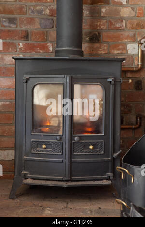 Wood burning multi-fuel stove fire flames raging behind the glass door  panel on a cold winter evening indoors at home fireside Stock Photo - Alamy