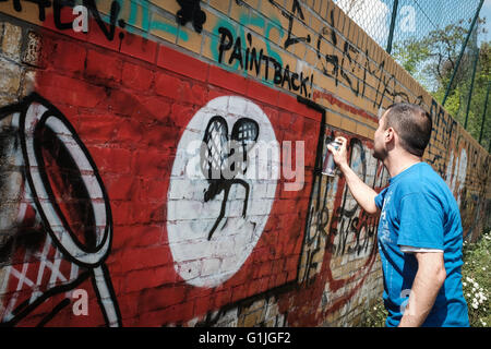 Graffiti artist Ibo Omari paints over swastika graffiti on a wall in Berlin, Germany, 11 May 2016. A local club has launched an initiative that will see Nazi symbols painted over. Photo: SOPHIA KEMBOWSKI/dpa Stock Photo