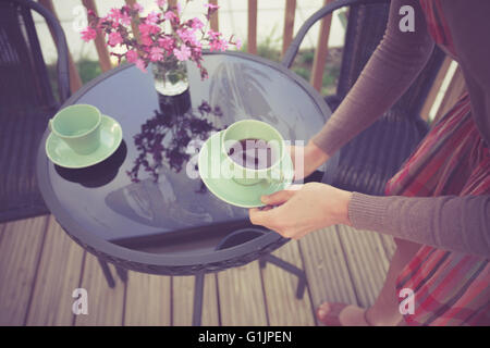 A young woman is setting the table for tea outside on the porch Stock Photo