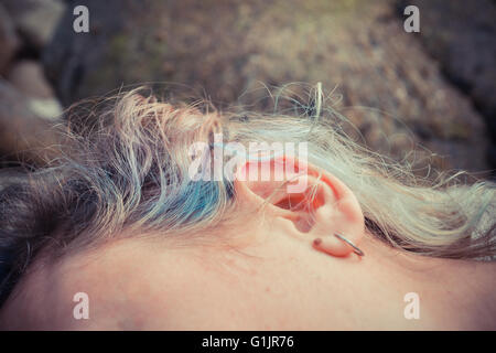 Closeup on a young woman's ear as she is lying outside Stock Photo