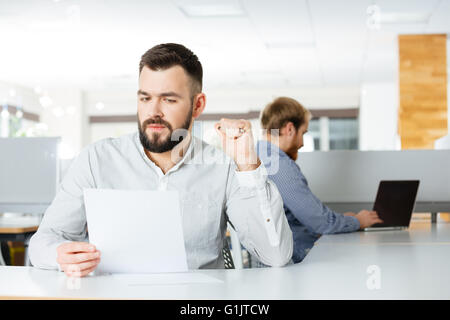 Serious handsome young businessman working with documents in office Stock Photo