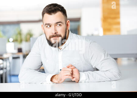 Happy bearded businessman in white shirt sitting at the table in office Stock Photo
