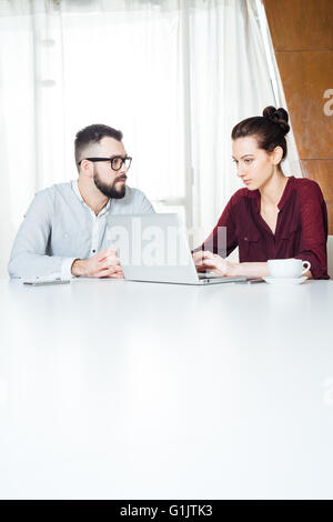 Two focused young businesspeople working and using laptop on the meeting in office Stock Photo