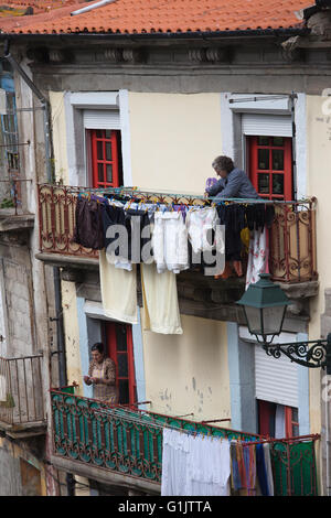 Portugal, city of Porto, women hanging laundry for drying on house balcony, daily routine activity Stock Photo