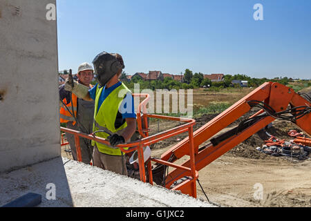 High elevated cherry picker with team of workers on construction site. Stock Photo