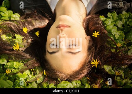 beautiful girl lying on grass with flowers Stock Photo