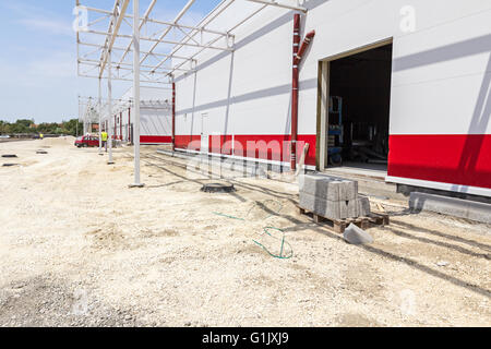 Kerb stones on pallet placed at gravel ground at road construction site. Stock Photo