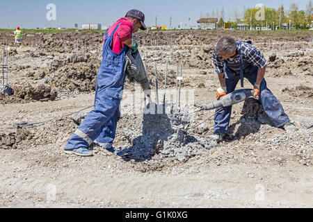 Construction workers are holding jackhammer and breaking reinforced pillars in the ground Stock Photo