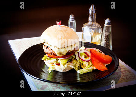 Large burger with cheese, lettuce, tomato, onion and gherkin Stock Photo