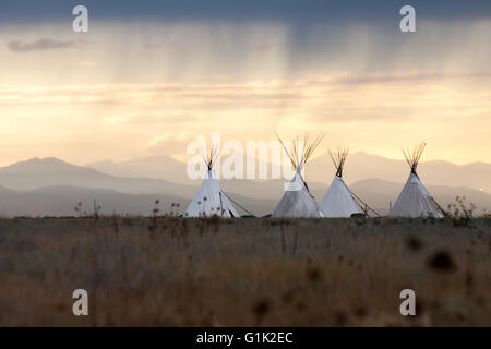 Teepees at sunset on the plains of Colorado beneath a passing rainstorm. Stock Photo